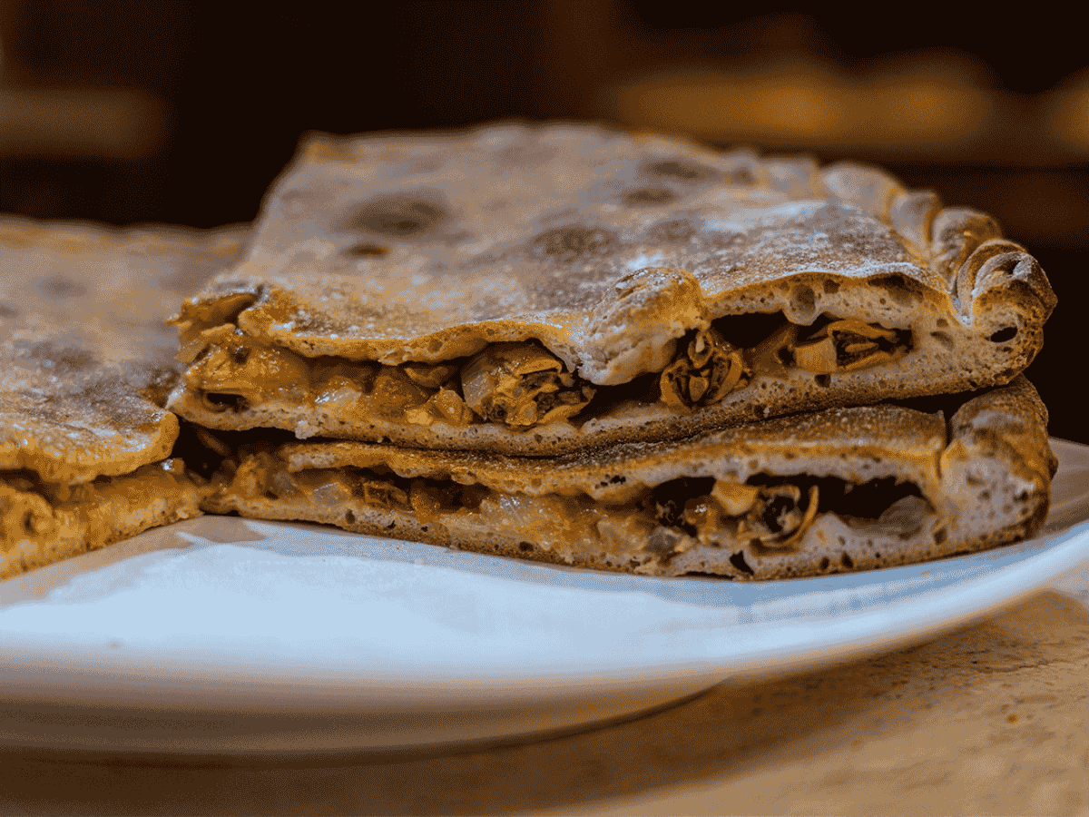 Empanada galega de mexillóns cortada amosando o recheo