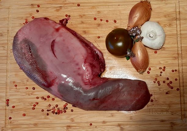 Lingua de tenreira crúa sobre táboa con allo, cebola e tomate