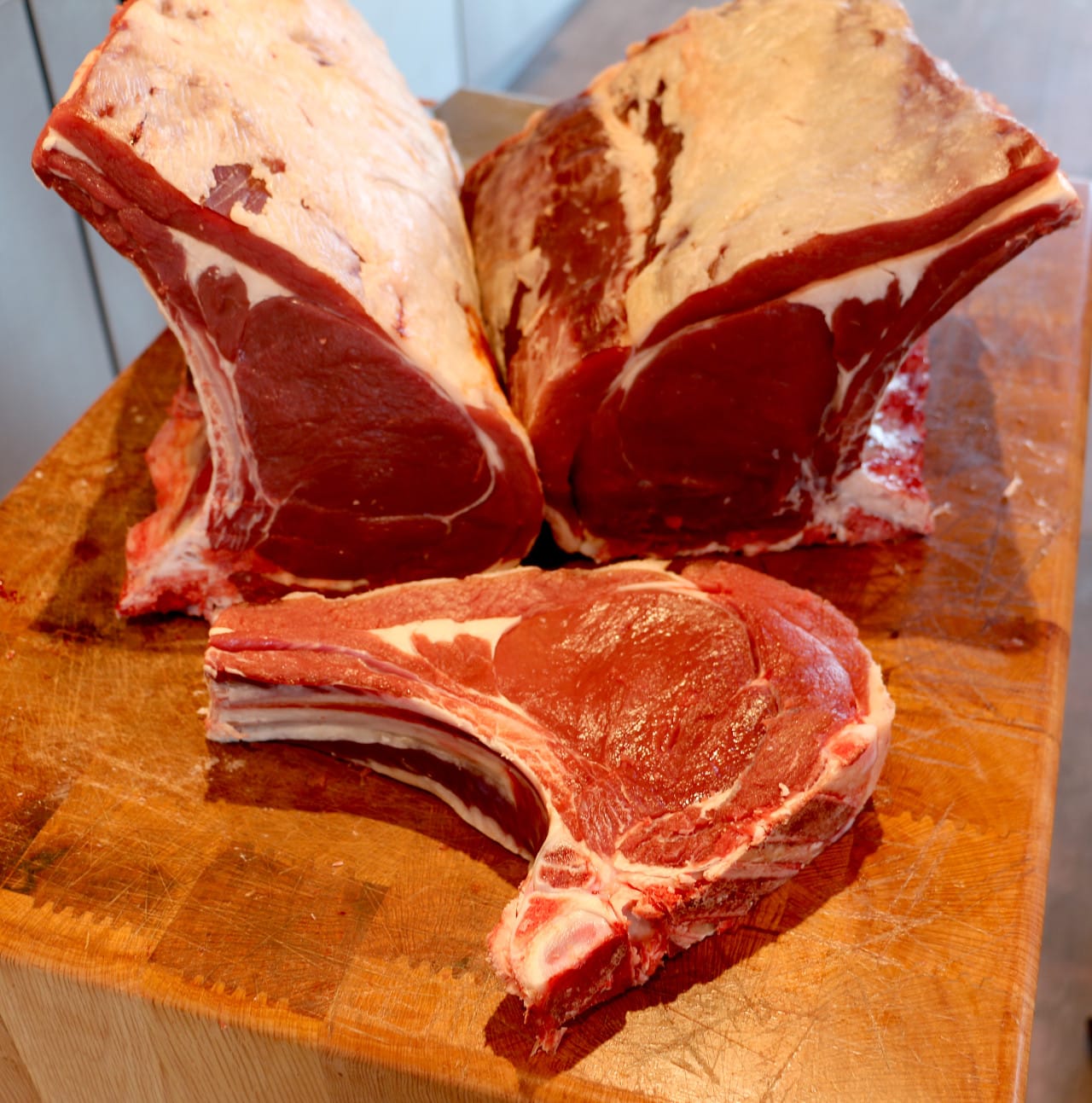 Tres chuletóns crus de tenreira sobre táboa de madeira
